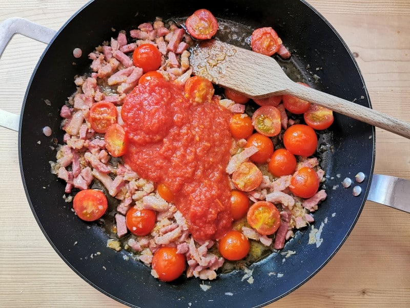 cherry tomatoes, tomato passata in skillet with onion and pancetta