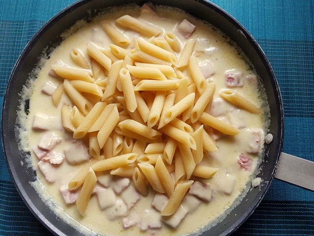 Penne being mixed into the Valdostana sauce