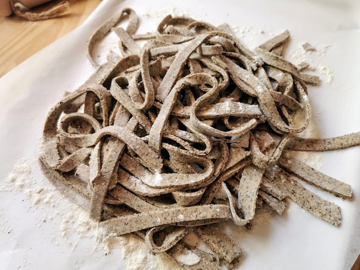 Ready homemade pizzoccheri pasta on flour dusted tray.