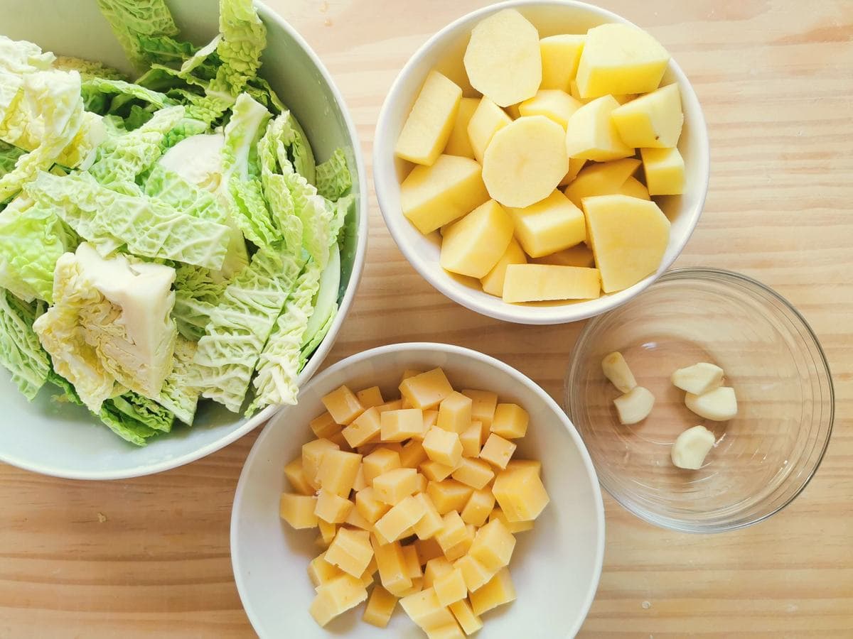 Prepare condiment ingredients for pizzoccheri alla Valtellinese in white bowls.