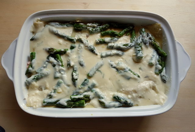 Poached salmon and asparagus lasagne al forno in white oven dish before baking