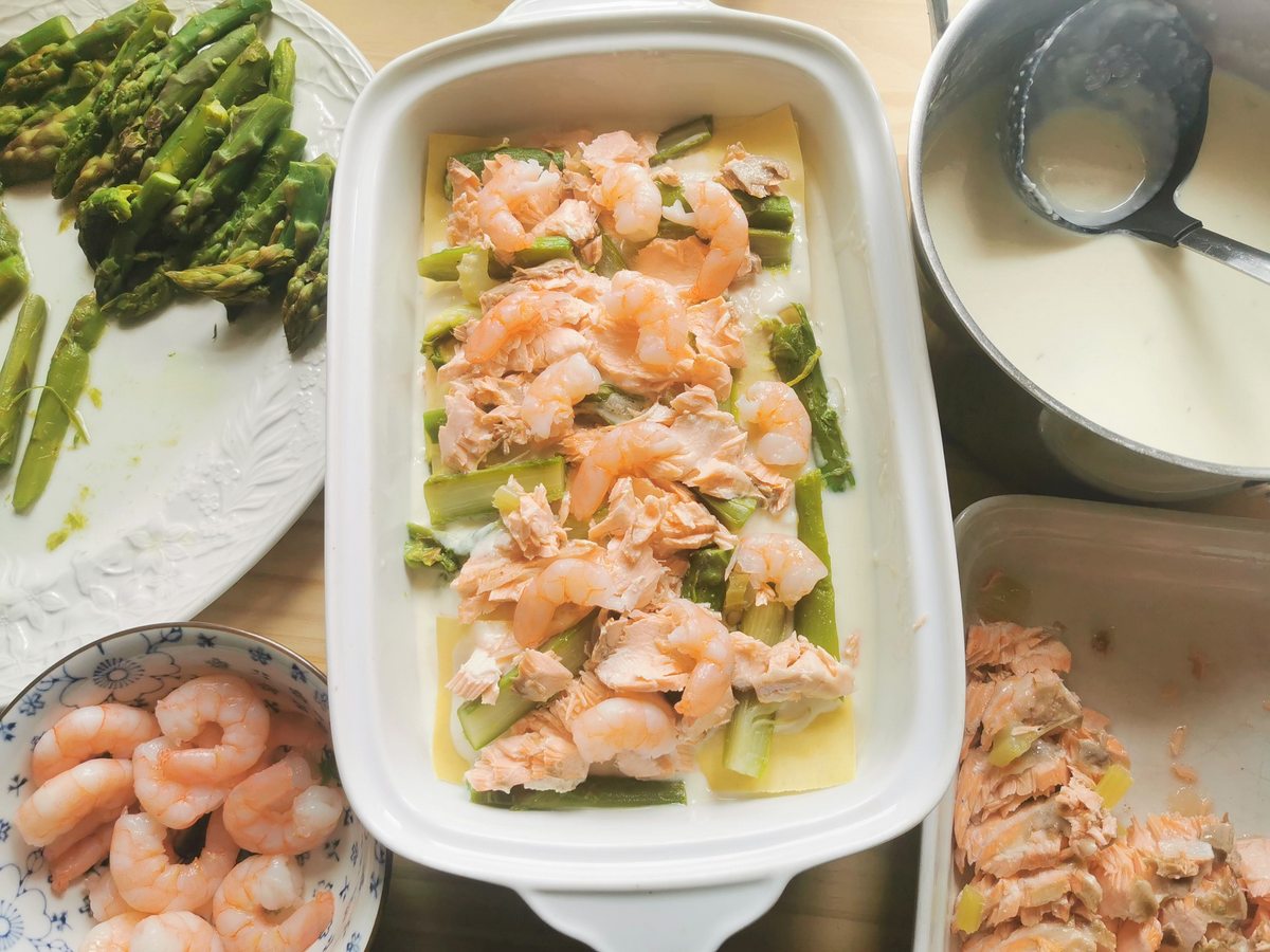 First pasta layer for salmon and asparagus lasagna with shrimps, poached salmon and asparagus pieces on top.