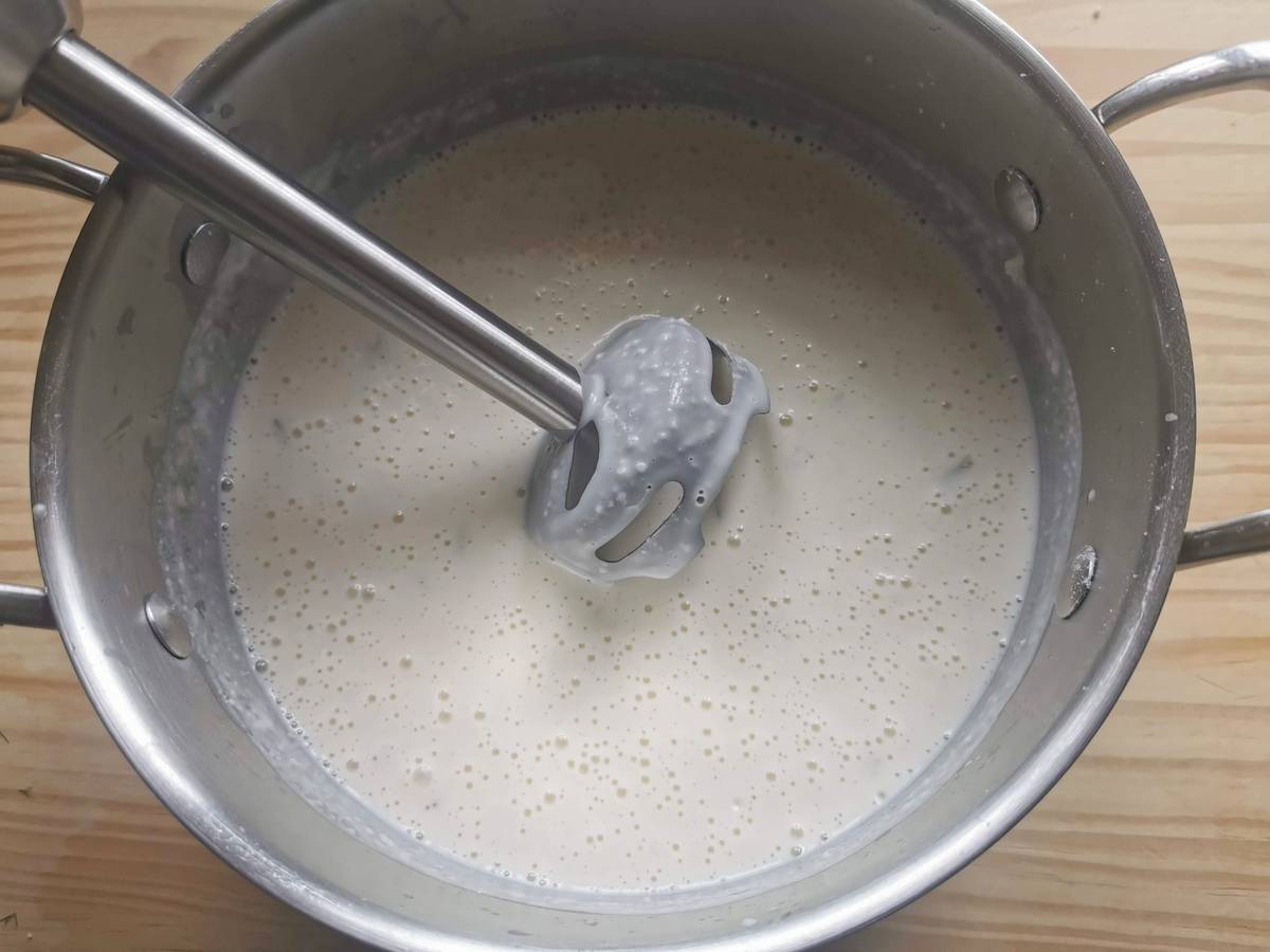 Ready creamed béchamel with stracchino in saucepan with handheld blender.