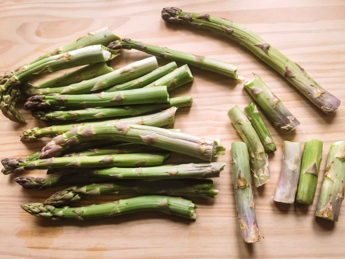 Fresh green asparagus with stalk ends broken off on wood worktop.
