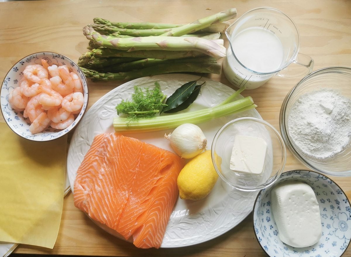Ingredients for poached salmon and asparagus lasagne al forno on wood worktop.