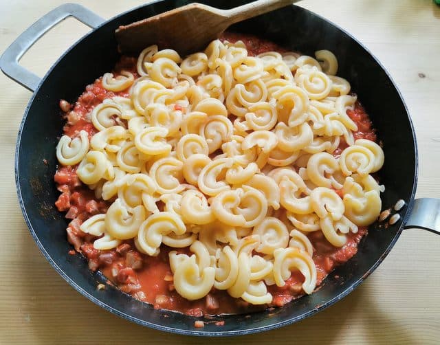 cooked dischi volanti pasta in skillet with ready ragu