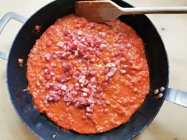 adding the rest of the prosciutto pieces to the ragu in skillet