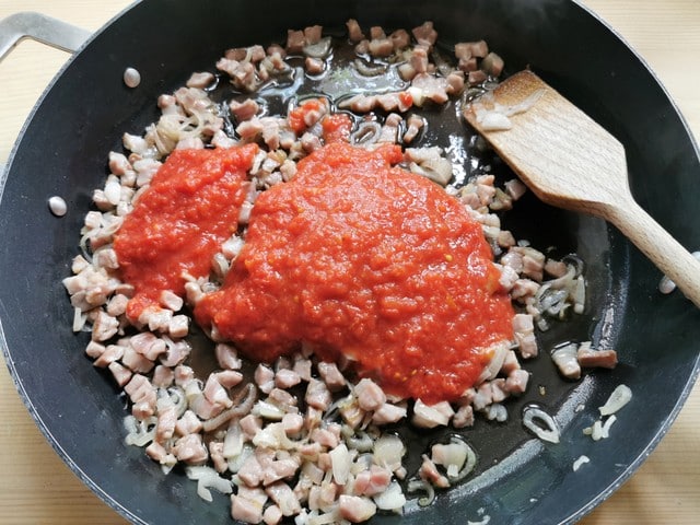 tomato passata with prosciutto and shallots in skillet