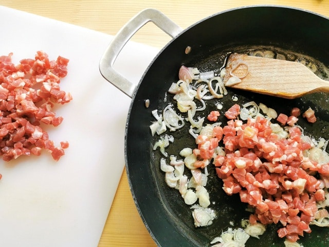 prosciutto pieces and chopped shallots frying in skillet