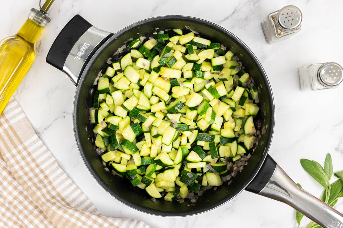 Tender zucchini in a large saute pan with softened red onions