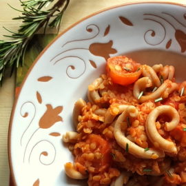 Red lentil ragu with whole-wheat pasta close up in white and terracotta bowl