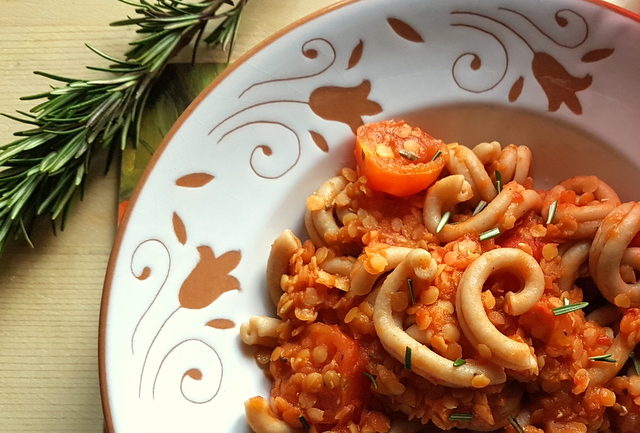 Red lentil ragu with whole-wheat intrecci pasta close up in white and terracotta bowl