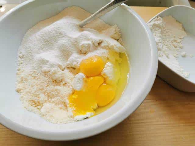 ricotta, eggs, parmigiano cheese and flour in white bowl