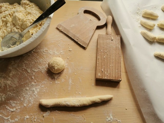 ricotta gnocchi being made floured on wooden board.