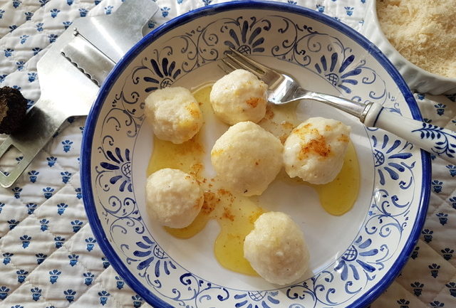 ricotta gnudi with browned butter on blue and white plate