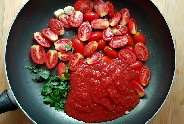 cherry tomatoes, tomato passata, garlic and chopped basil in frying pan