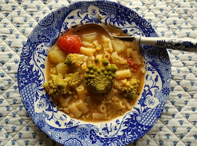 Romanesco broccoli pasta soup in blue and white bowl