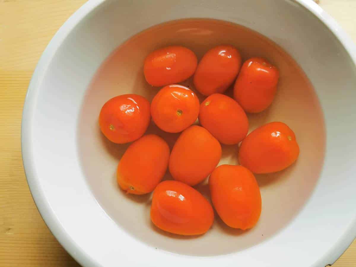 fresh tomatoes in white bowl with boiling water
