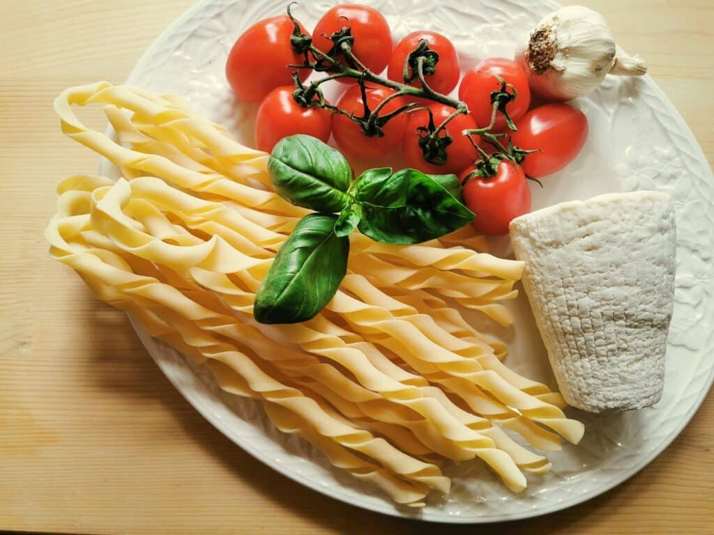 ingredients for sagne torte with tomato sauce and strong ricotta on white plate