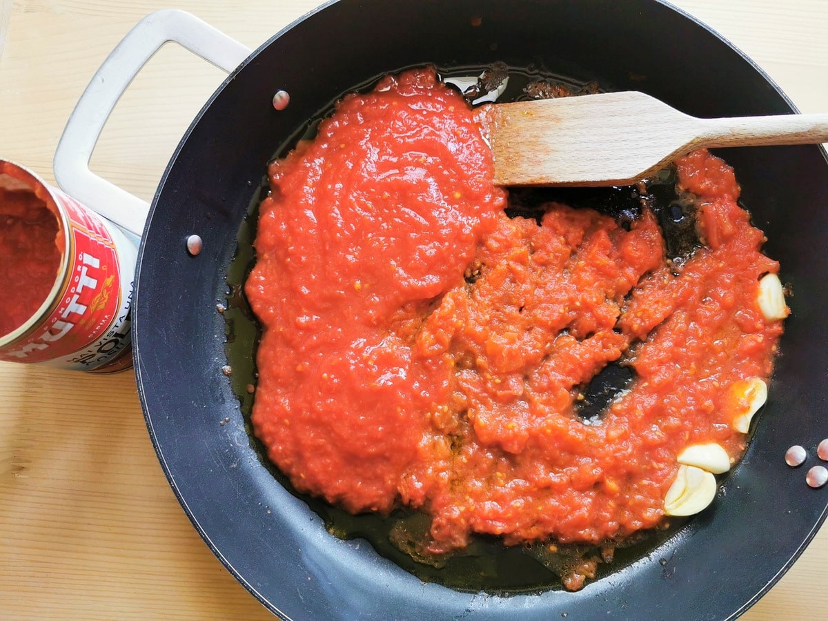 tomato passata added to skillet with chopped tomatoes and garlic