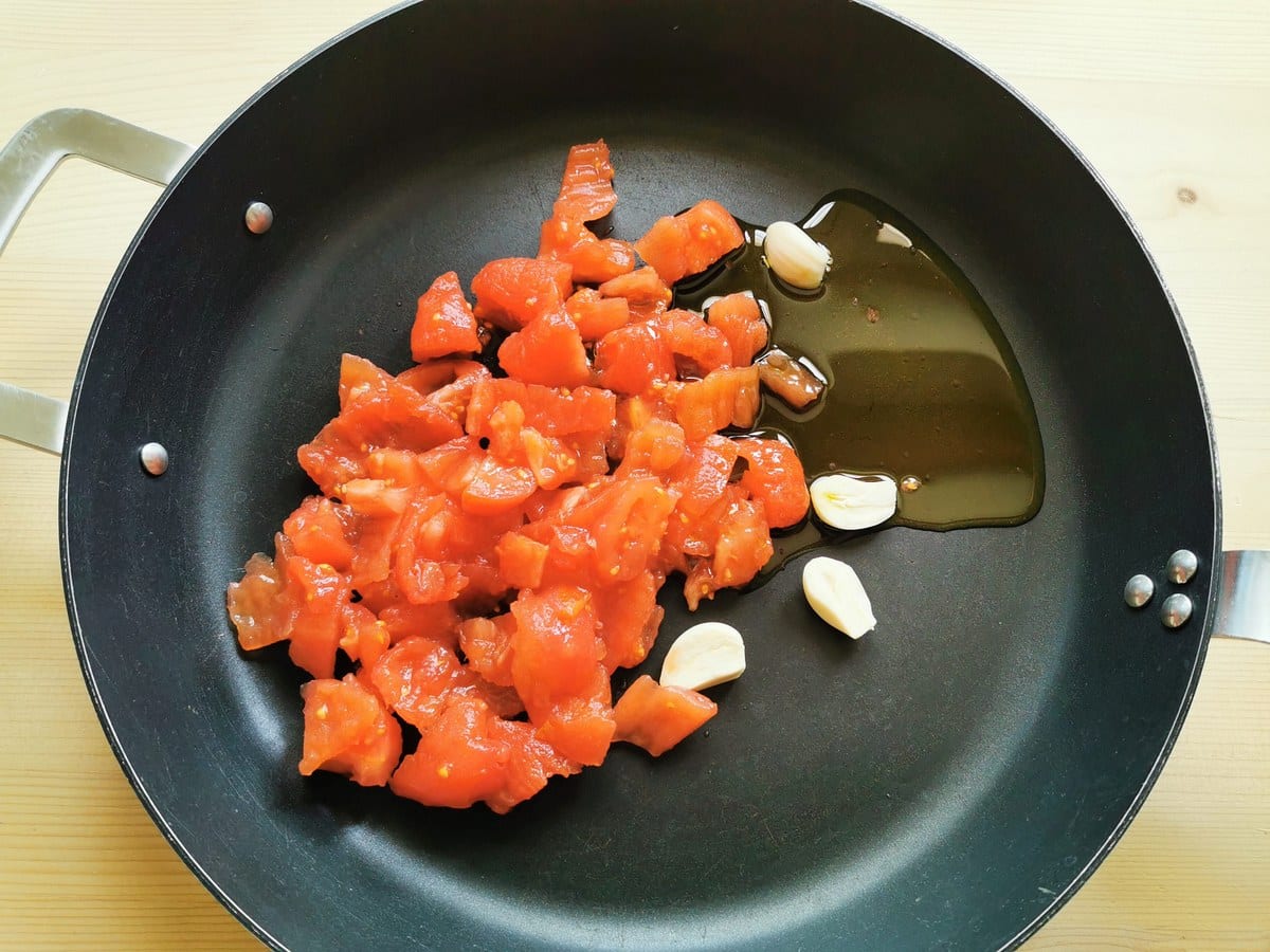 chopped tomatoes in skillet with garlic and olive oil