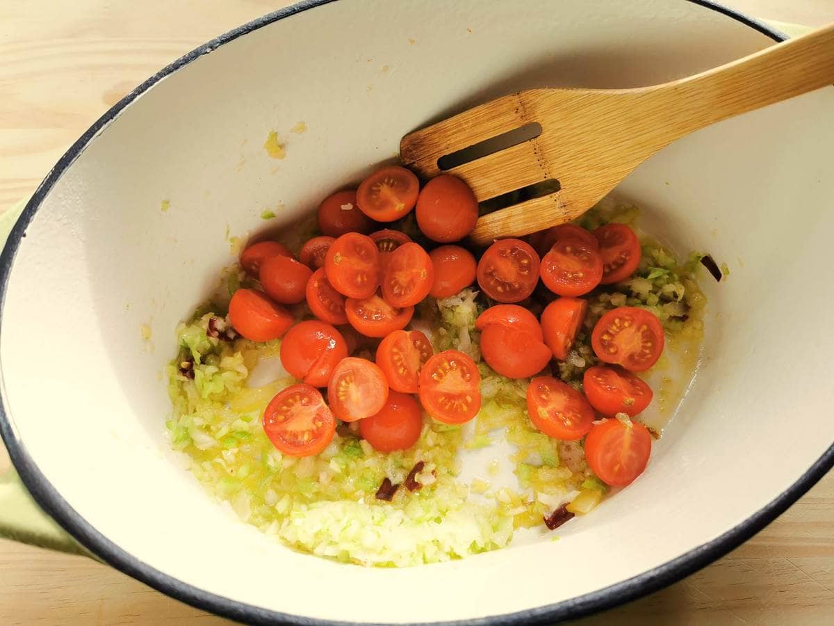 Halved cherry tomatoes added to the Dutch oven with the onions, garlic, celery and peperoncino.