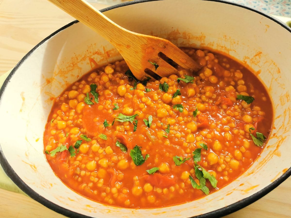 Fregola with chickpeas (pasta e ceci) in Dutch oven with fresh parsley sprinkled on top.