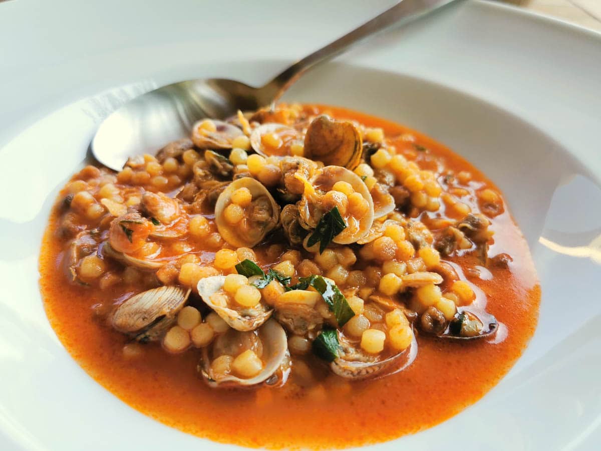 Fregola with clams in a white bowl