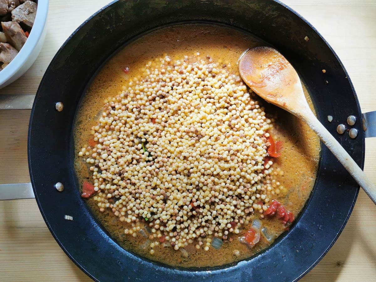 Fregola being added to the sauce