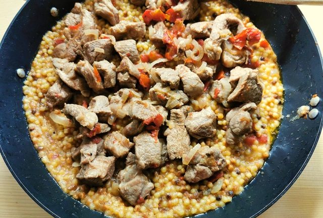 cooked lamb cubes and cooked fregola together in skillet