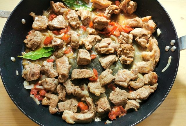lamb cubes, onions, sun-dried tomatoes and bay leaves cooking in skillet