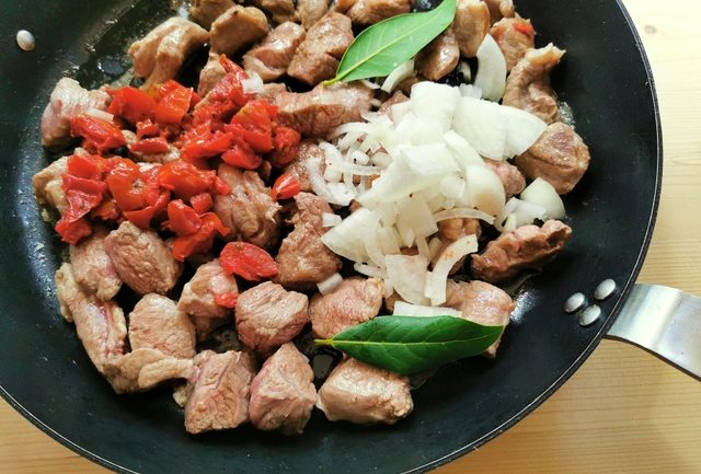 lamb cubes, onions, sun-dried tomatoes and bay leaves in skillet