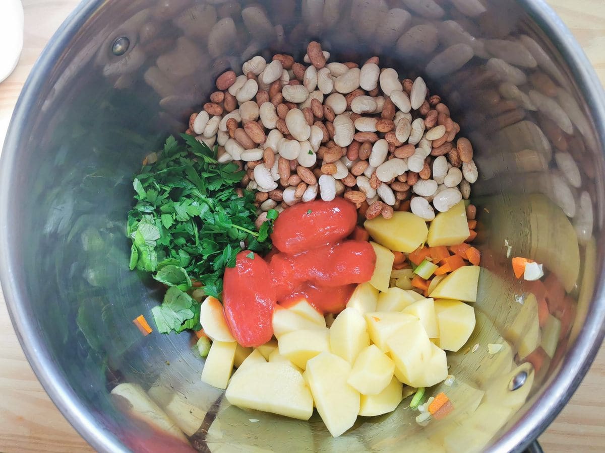 Soaked beans and chickpeas, herbs, potatoes and canned tomatoes in large pot with chopped carrots, celery and onion.