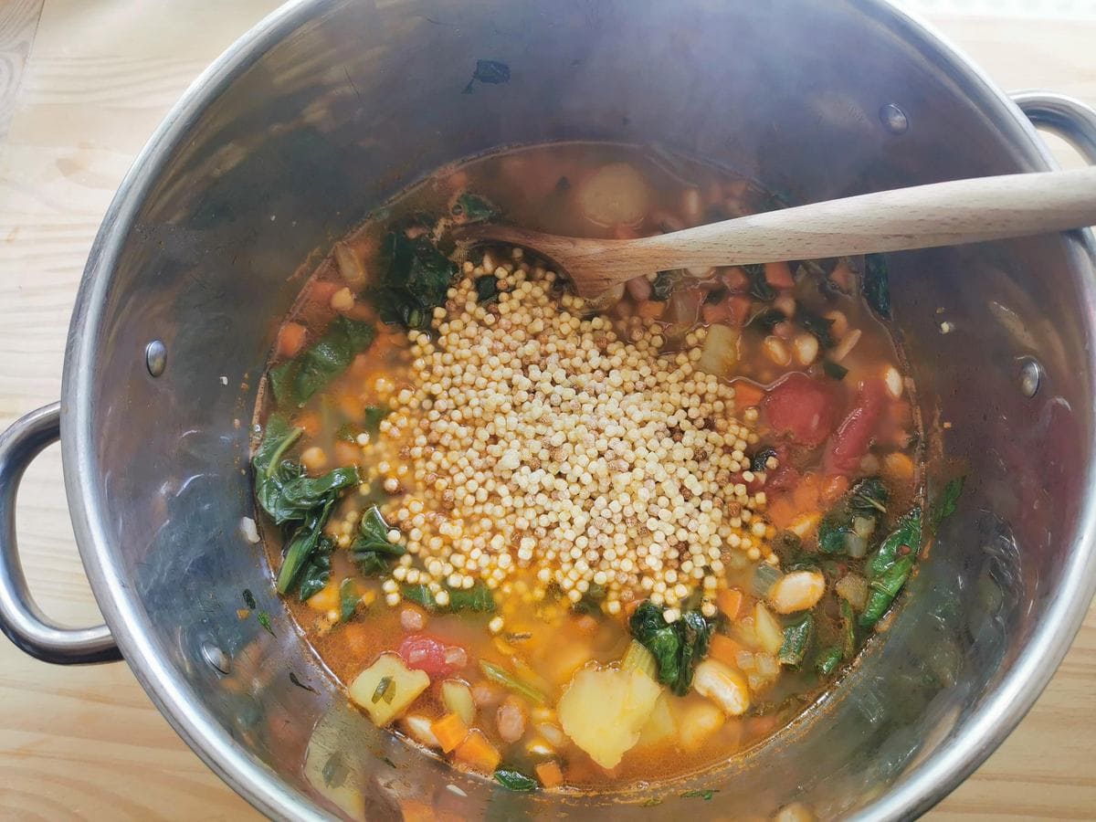 Fregola pasta added to pot with Sardinian minestrone soup.
