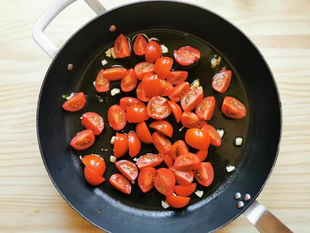 Chopped tomatoes and garlic cooking in skillet