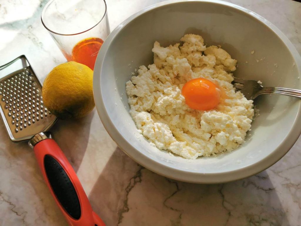 Fresh sheep ricotta and egg yolk in white bowl for ravioli filling