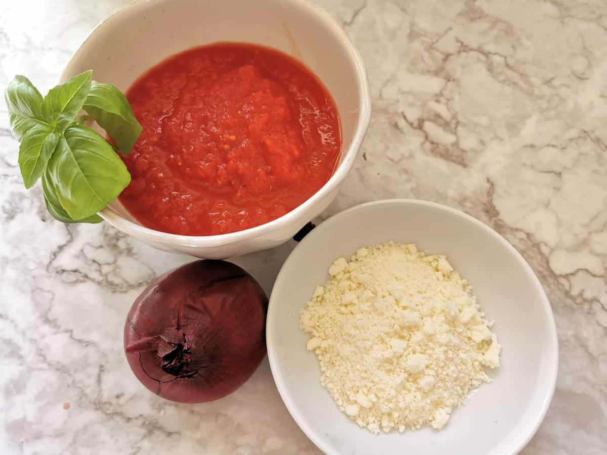 ingredients for tomato sauce in white bowls