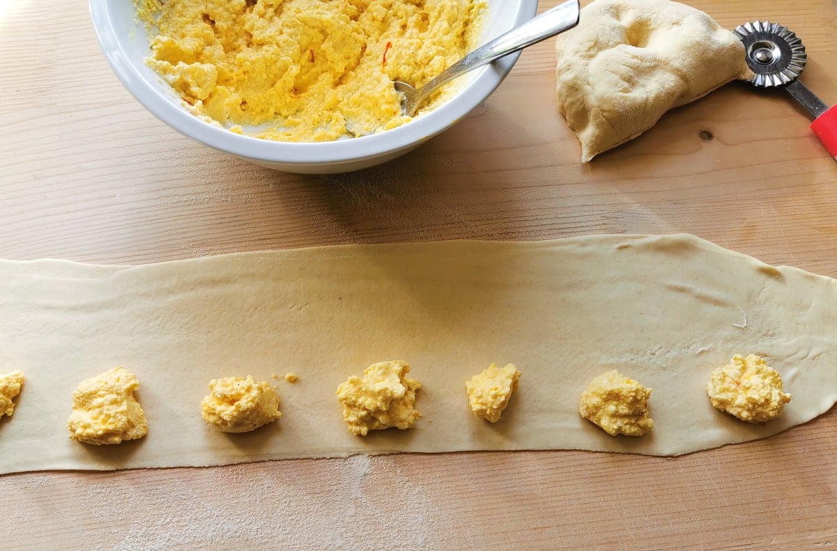 rolled out pasta sheet with teaspoons of filling along one side