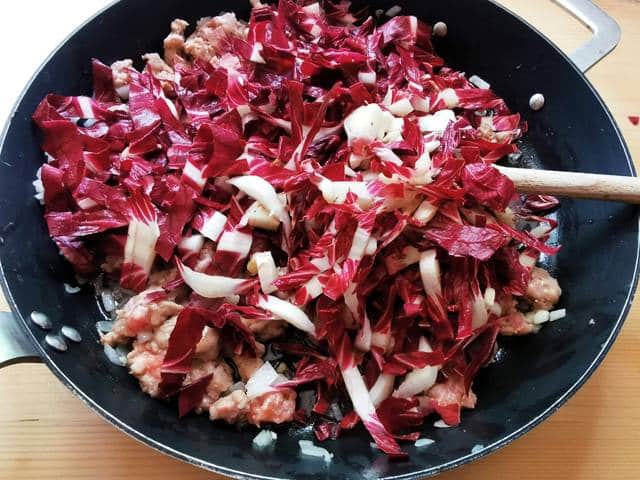 uncooked radicchio in skillet with onions and sausage meat