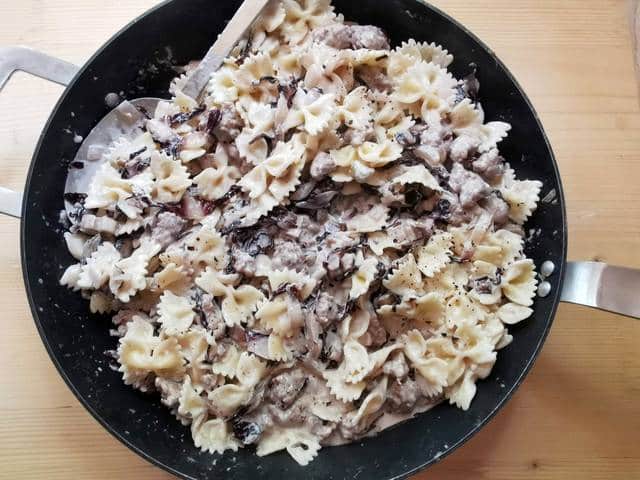 farfalle pasta mixed with sausage and radicchio sauce in skillet