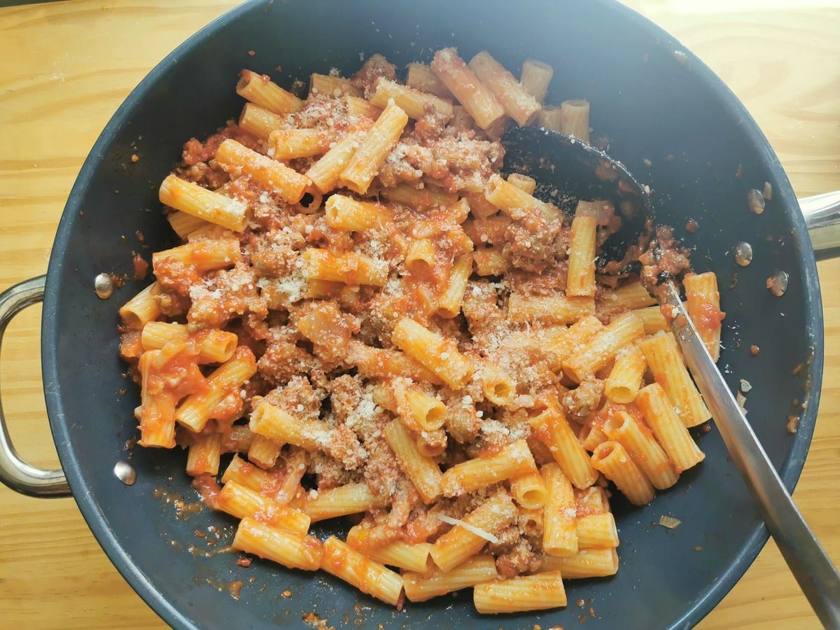 Rigatoni pasta alla zozzona in skillet with grated Pecorino sprinkled on top.
