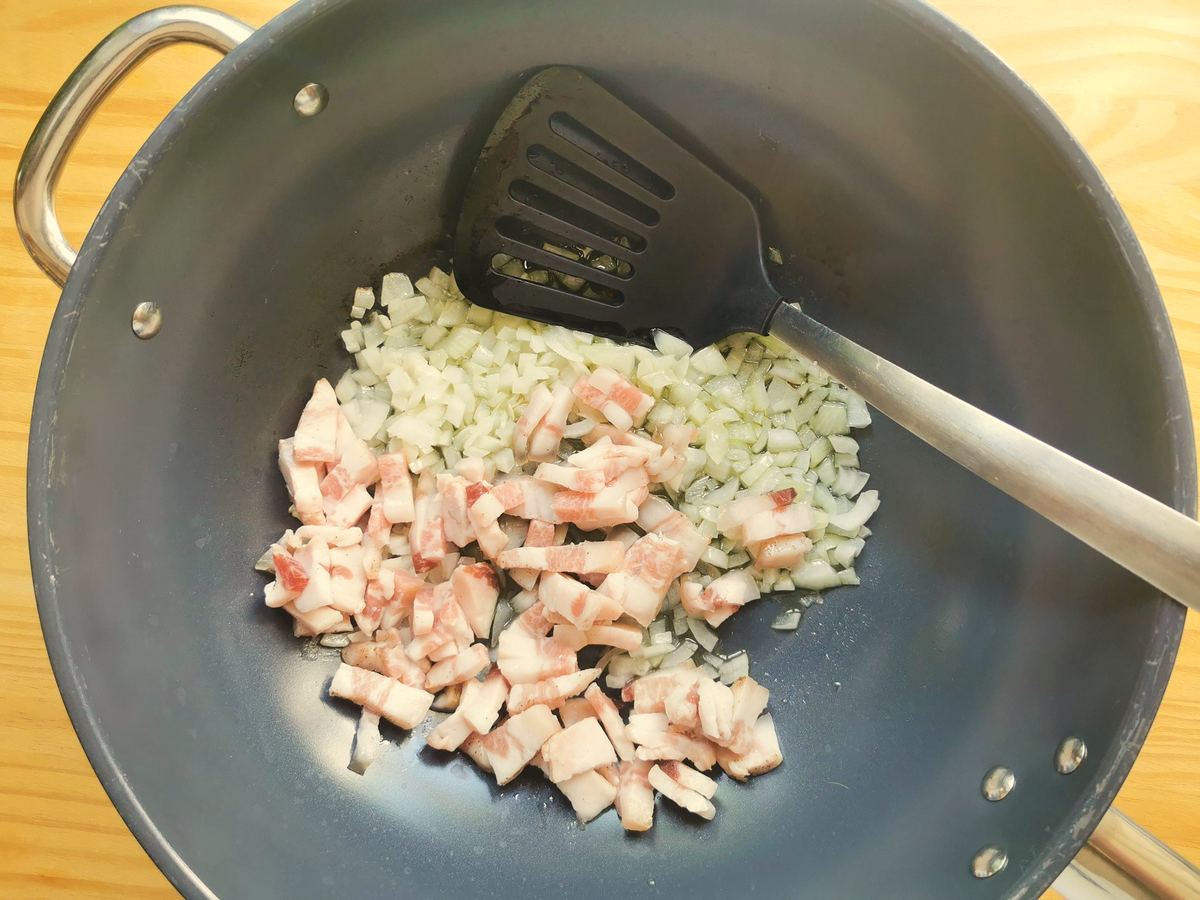 Diced onion and guanciale cooking in skillet with a little olive oil.