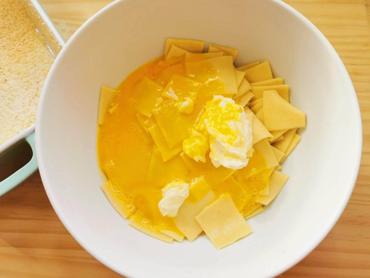 Egg yolks in white bowl with cooked fleckerl pasta squares and creamed butter.