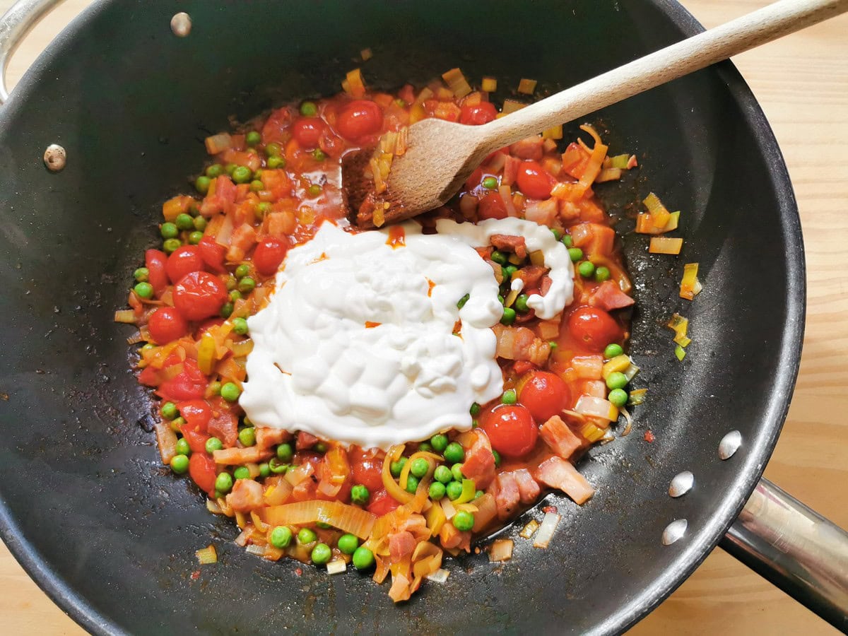 Heacvy cream added to seven Ps pasta sauce cooking in skillet.