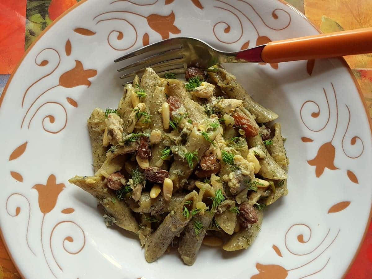 Penne pasta with sardines in a bowl with a fork.