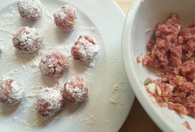 floured raw tuna meatballs on white plate. ready to fry.