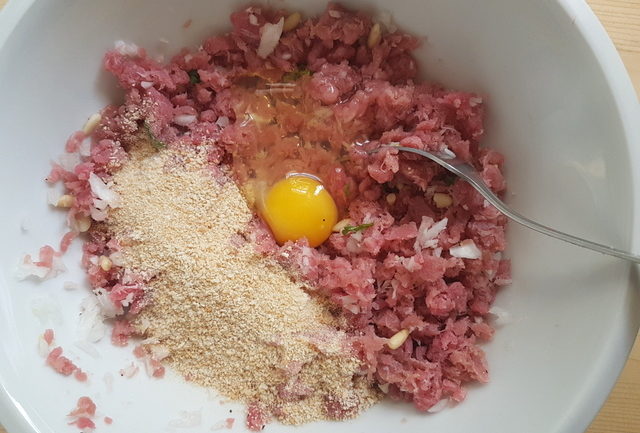 ground tuna mixture with raw egg and breadcrumbs  in white bowl