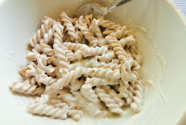 cooked fusilli mixed with ricotta in white bowl