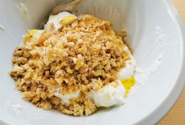 ground walnuts, garlic, olive oil and ricotta in white bowl