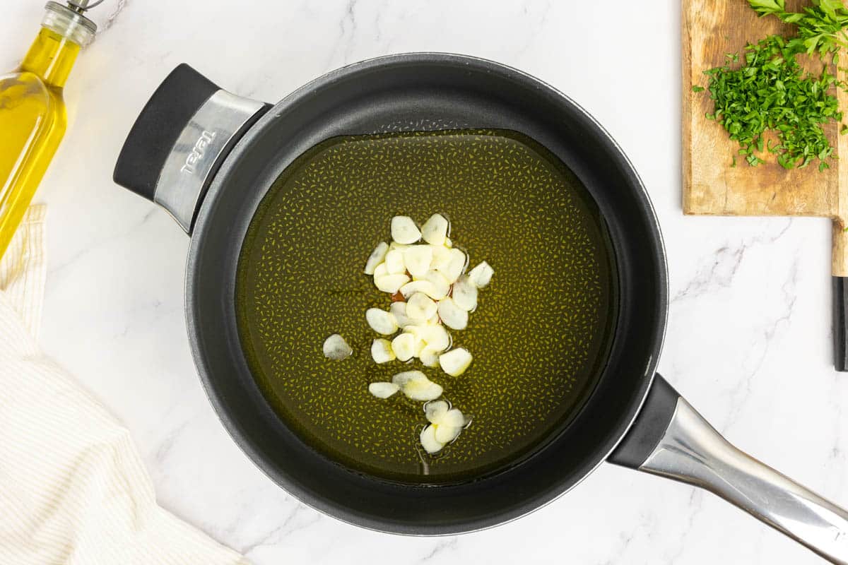 Add garlic to extra virgin olive oil in a large deep saute pan